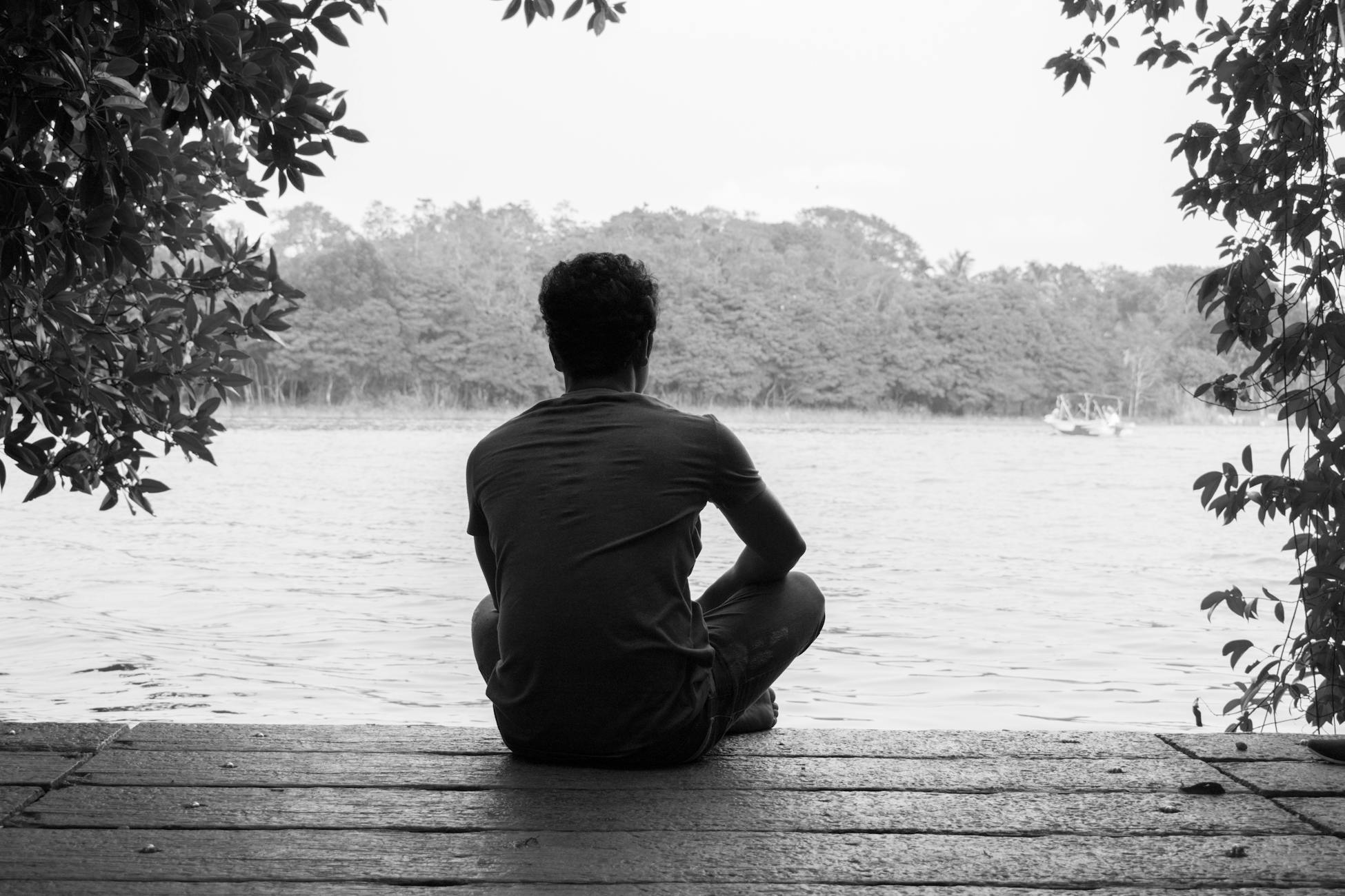 A person relaxes by a peaceful lake in Dambulla, Sri Lanka, surrounded by nature's beauty.