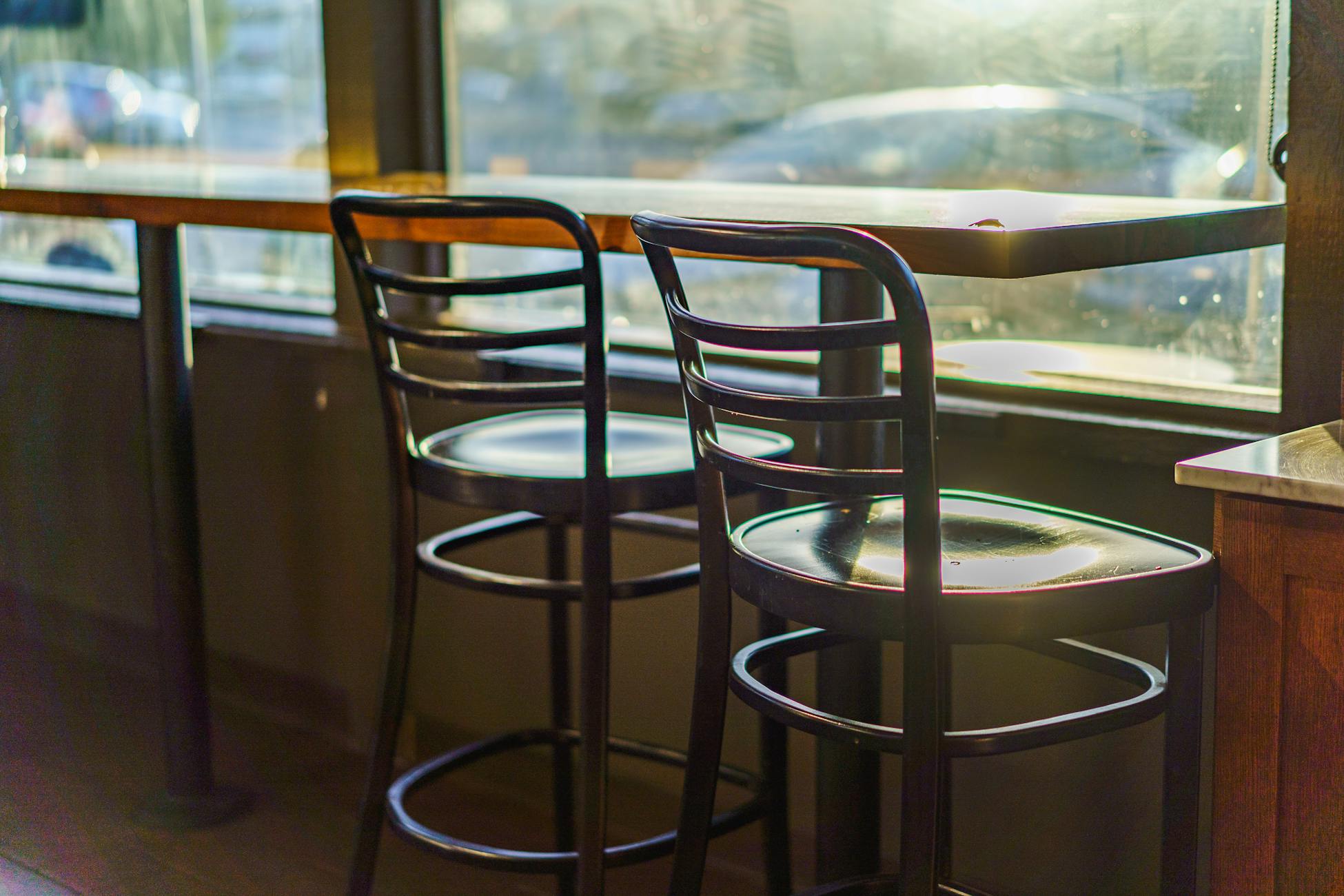 Two empty cafe chairs by a sunlit window, creating a warm and inviting atmosphere.