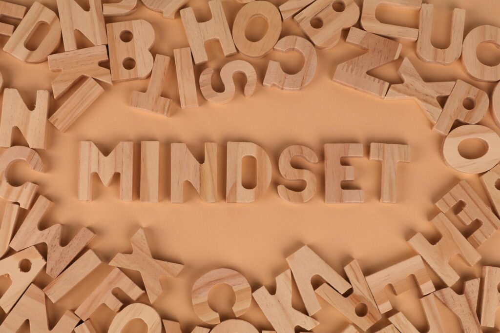 Wooden alphabet letters arranged to spell 'Mindset' on a peach background.