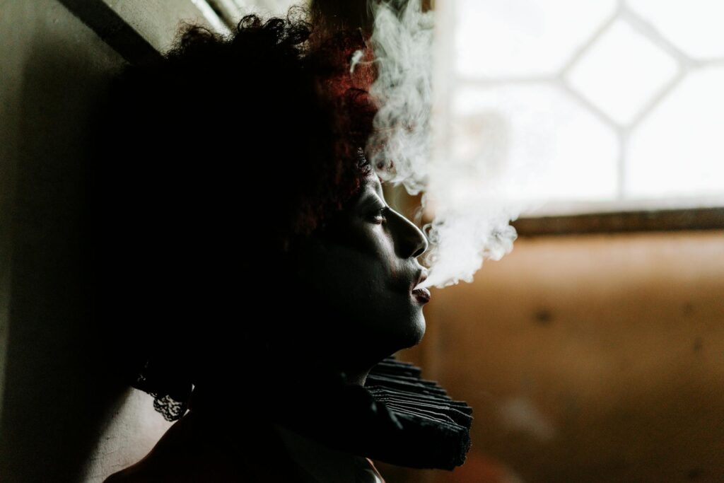 Side profile of a clown smoking indoors, creating a moody, dramatic atmosphere.