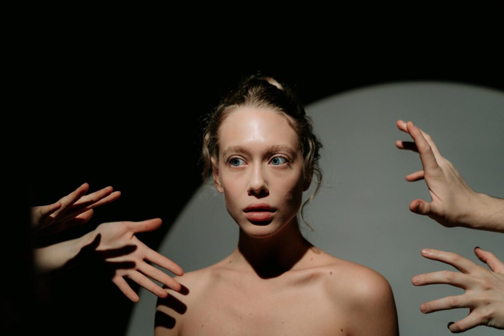 A conceptual portrait of a woman surrounded by hands, evoking a surreal, dreamlike atmosphere.
