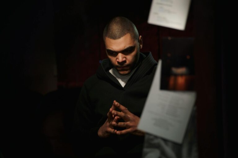 Portrait of a pensive man in moody lighting, conveying serious thought.