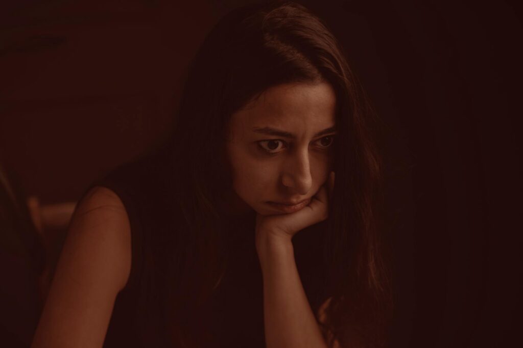 A thoughtful and introspective portrait of a woman leaning on her hand with a pensive expression.