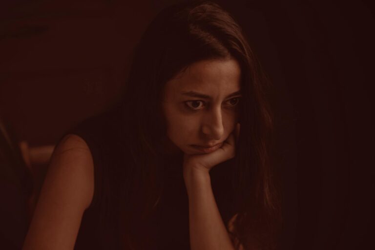 A thoughtful and introspective portrait of a woman leaning on her hand with a pensive expression.