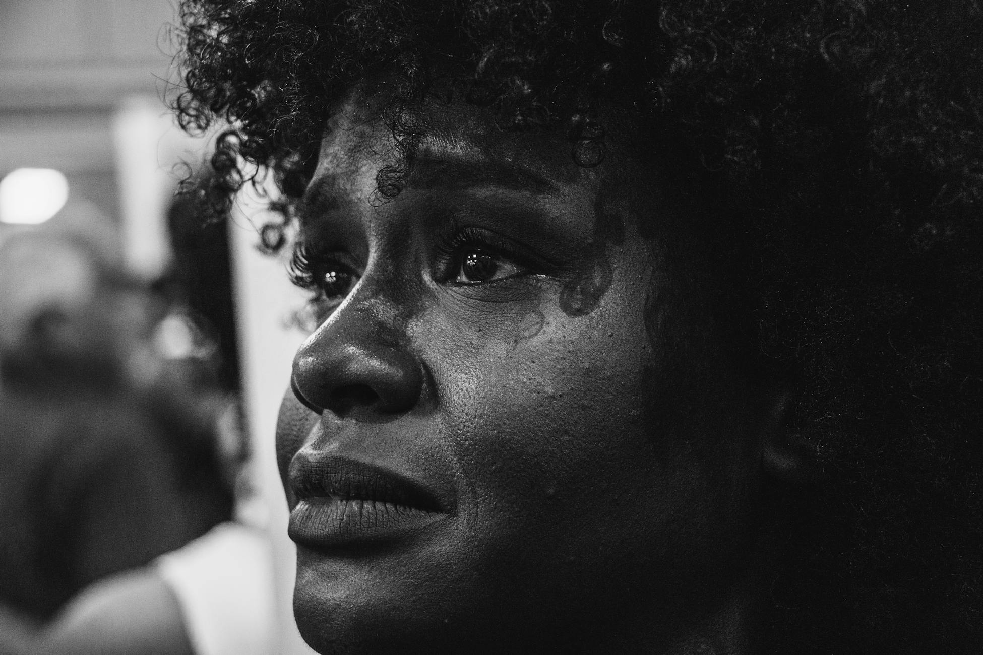 Close-up grayscale portrait capturing deep emotion on a woman's face.