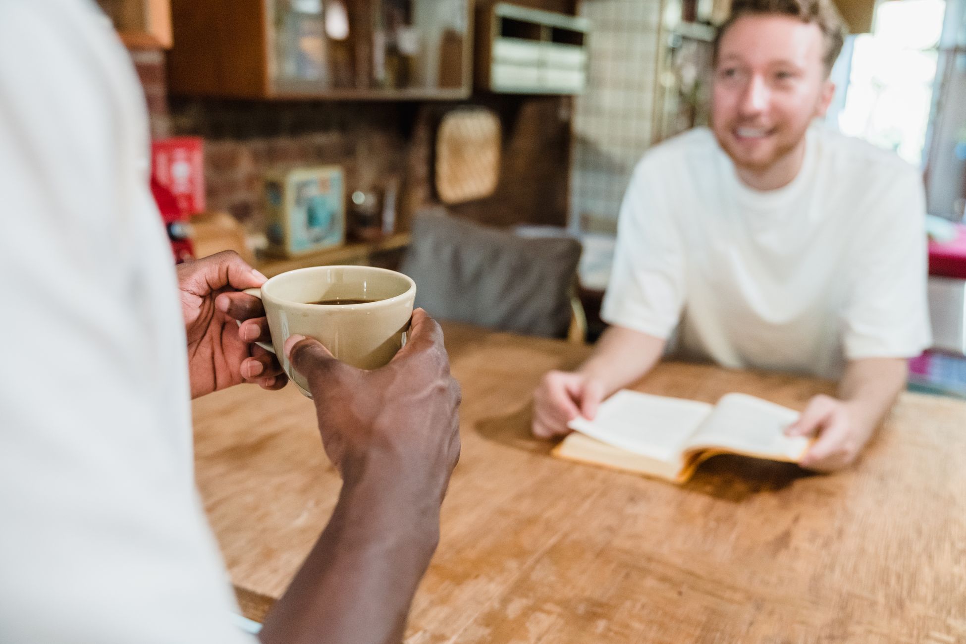 Two men enjoying coffee and conversation in a warm kitchen environment, embodying a relaxed lifestyle.