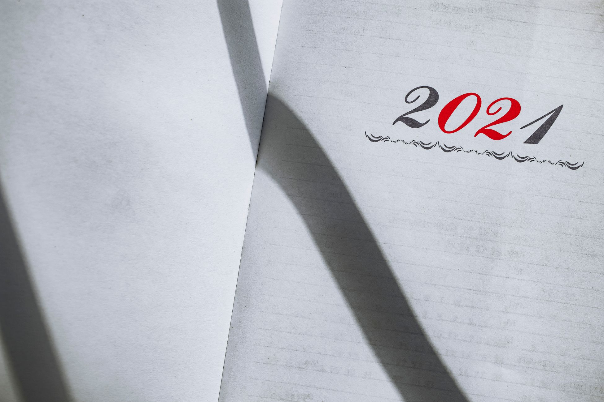 Close-up of an open planner showing the year 2021 with minimalist styling and shadows.