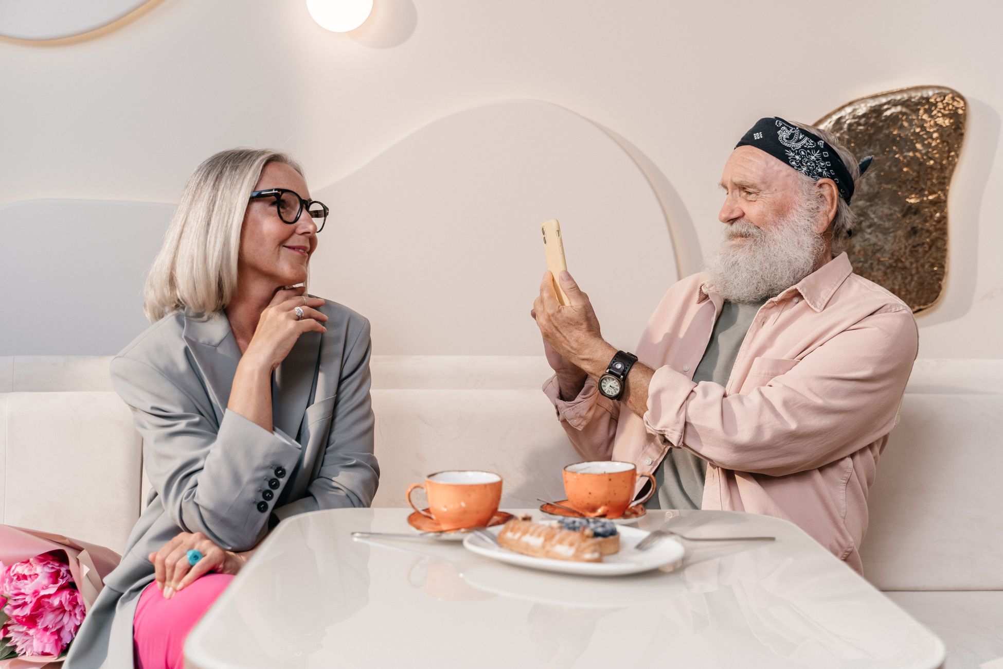 Senior couple in a stylish cafe enjoying each other's company over coffee and pastries.