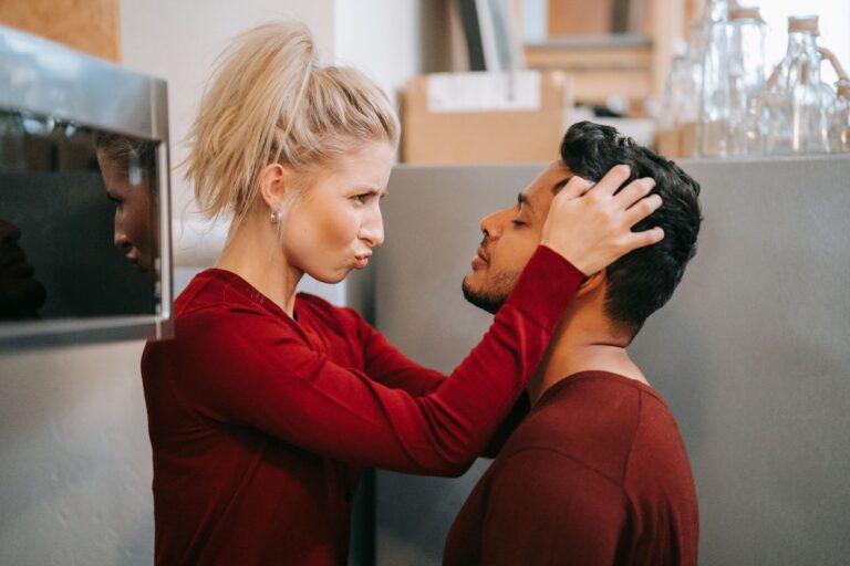 A playful couple shares a tender moment in a cozy indoor setting, showcasing love and affection.