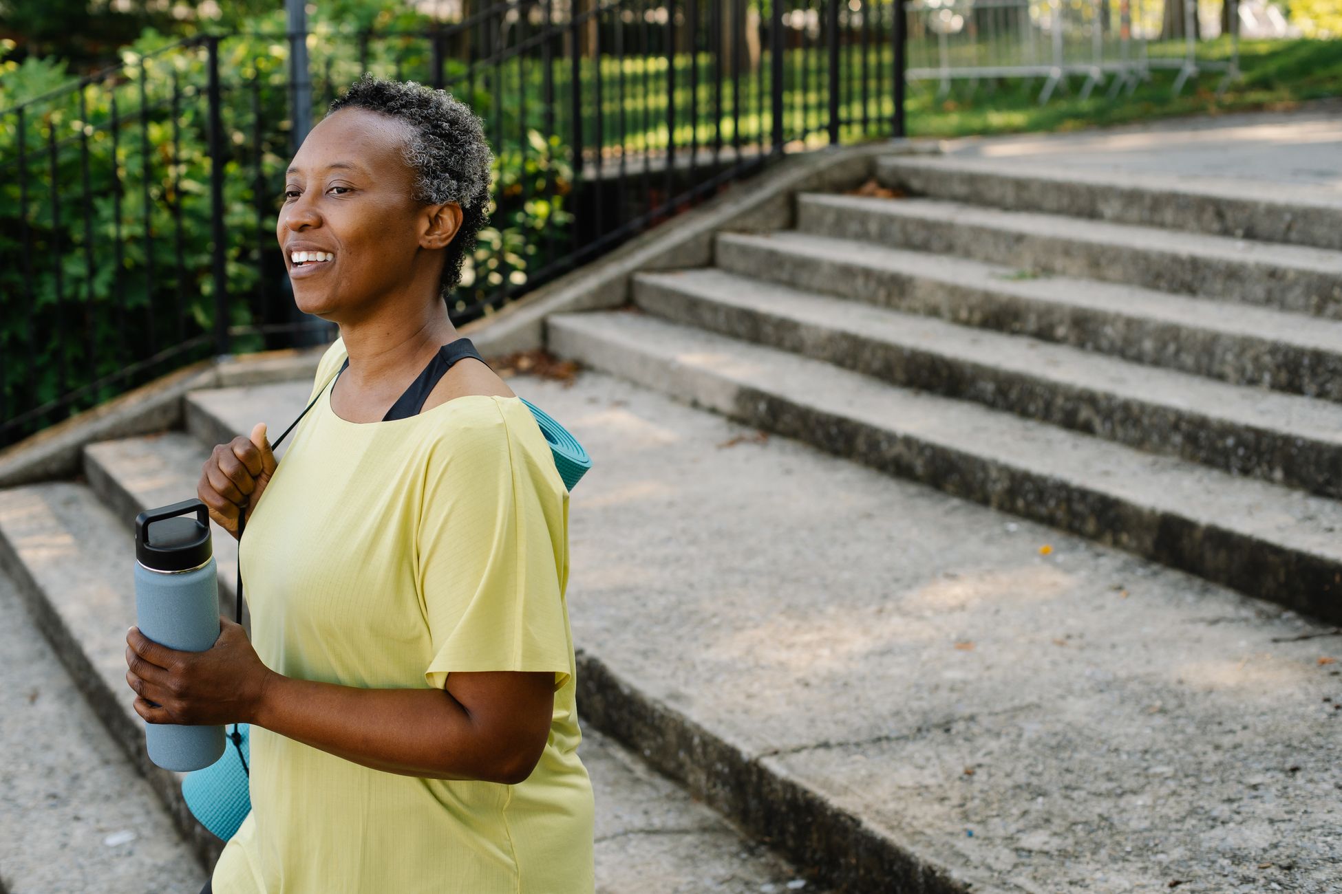 Senior woman exercising outdoors, smiling, holding a water bottle. Perfect for lifestyle and fitness themes.