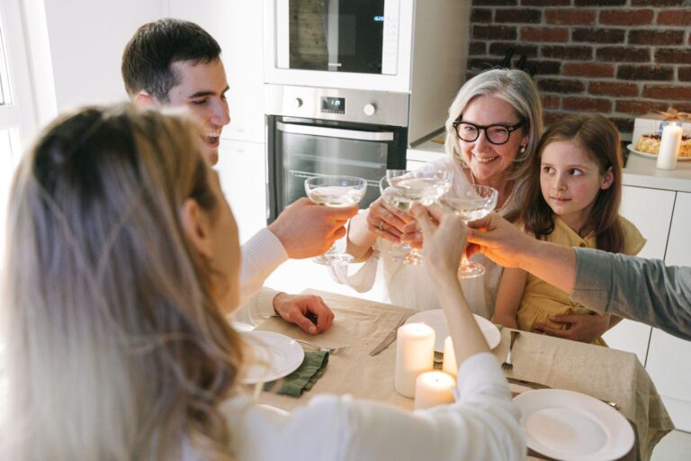 Family gathering with multiple generations toasting together around a dining table with candles.