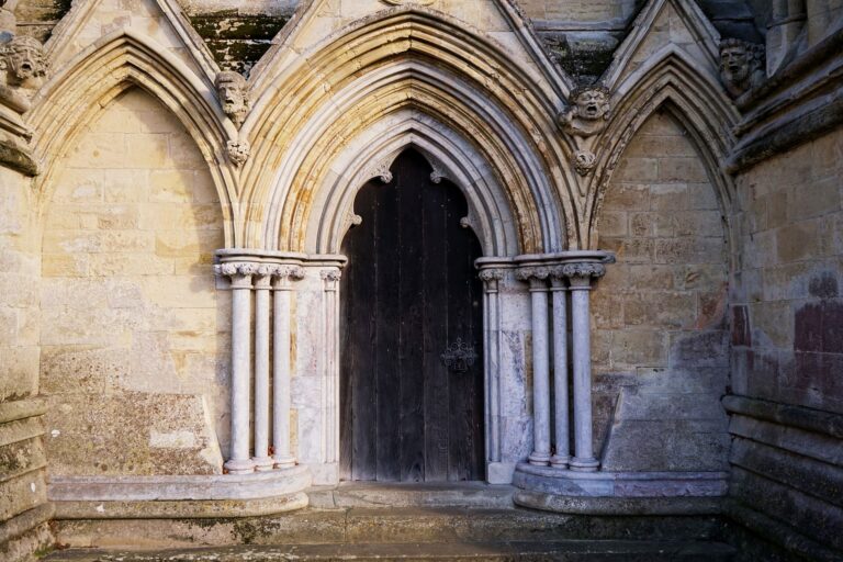 Stone doorway with Gothic arches at Salisbury Cathedral, showcasing intricate architecture.